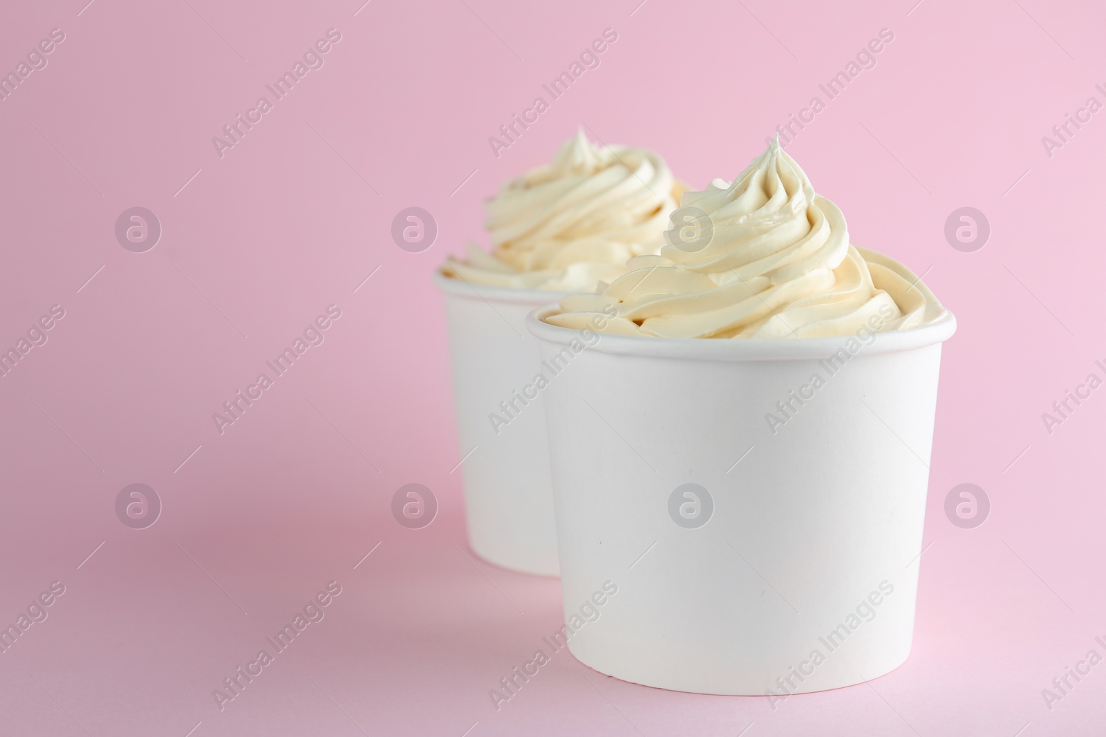 Photo of Cups with tasty frozen yogurt on pink background. Space for text