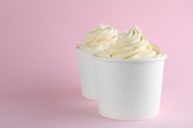 Cups with tasty frozen yogurt on pink background. Space for text