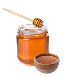 Natural honey dripping from dipper into wooden bowl. Jar full of honey on white background