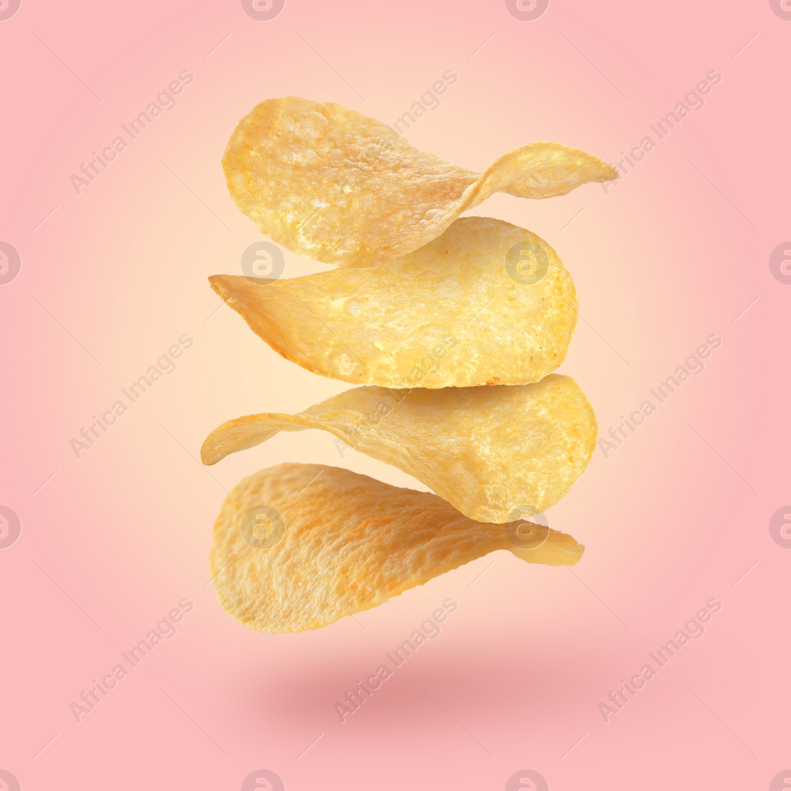 Image of Stack of tasty potato chips falling on pink background