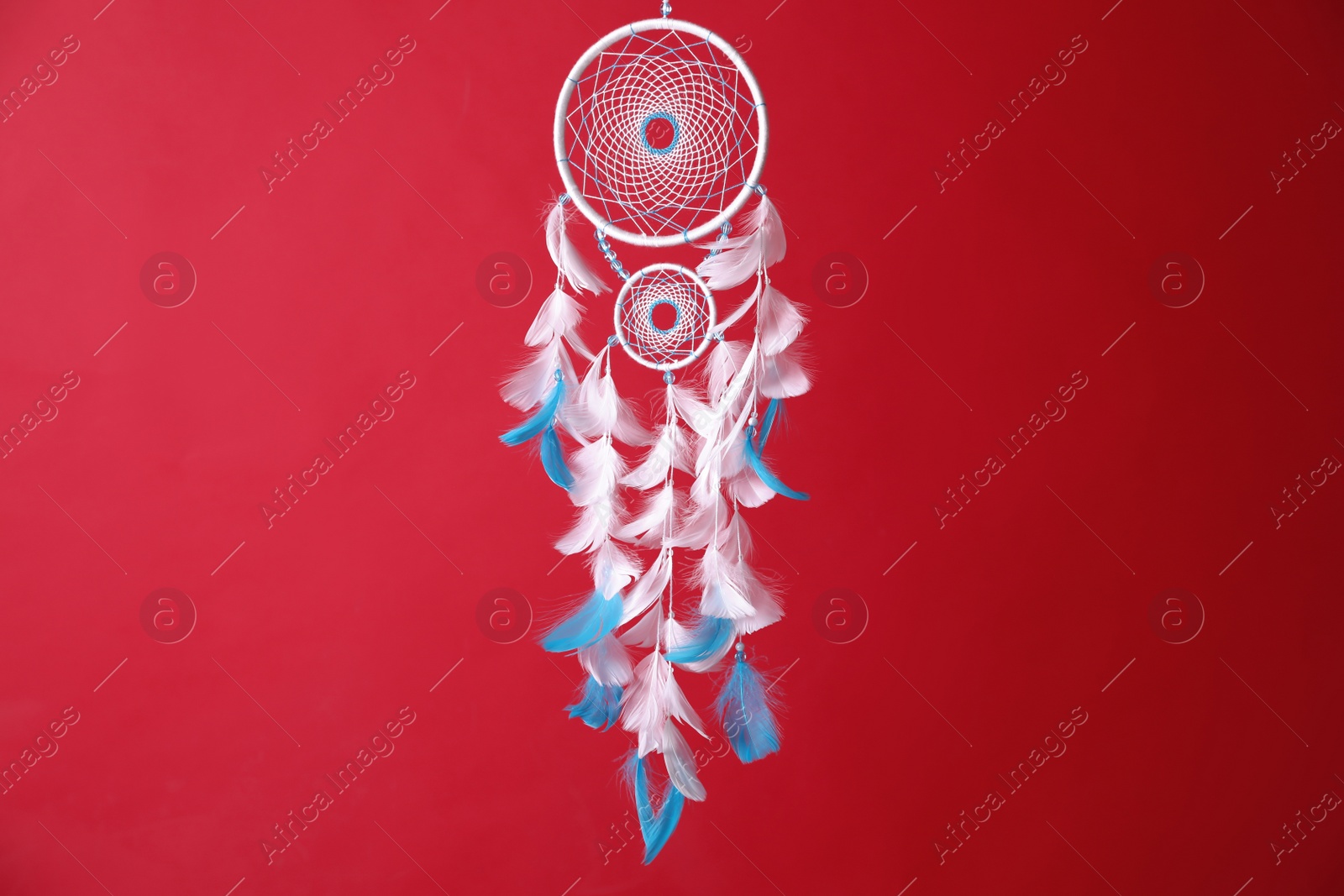 Photo of Beautiful dream catcher hanging on red background