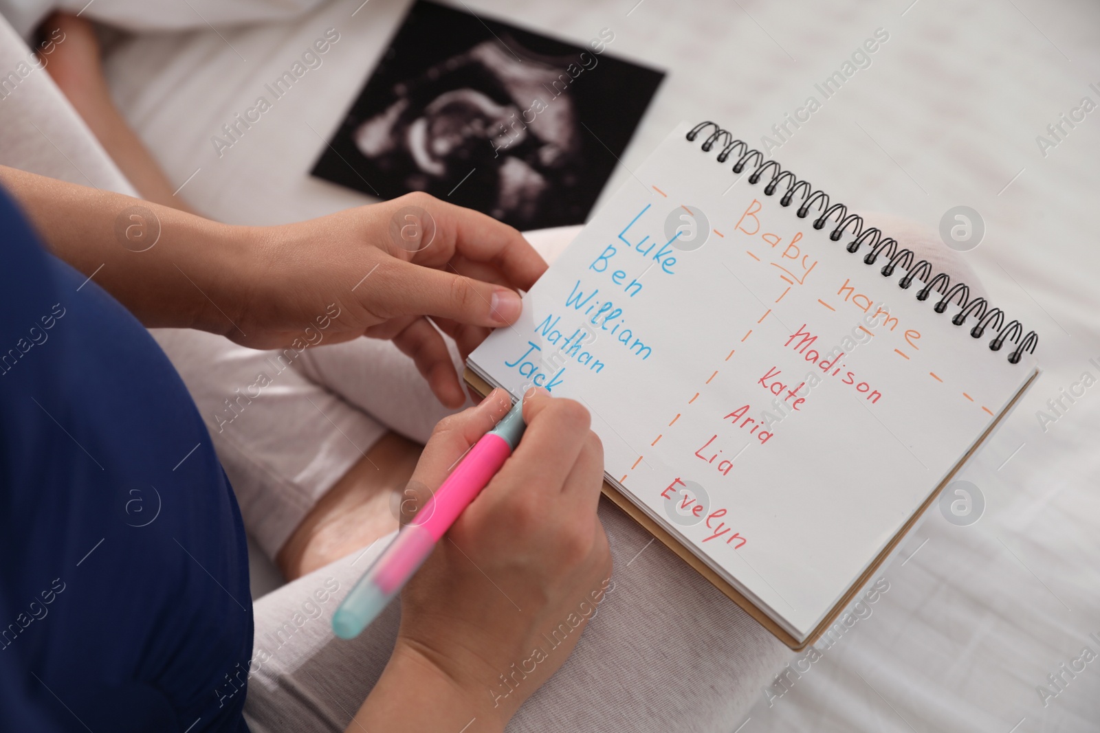 Photo of Pregnant woman with baby names list sitting on bed, closeup