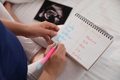 Photo of Pregnant woman with baby names list sitting on bed, closeup