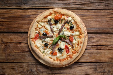 Photo of Tasty pizza with anchovies, basil and olives on wooden table, top view