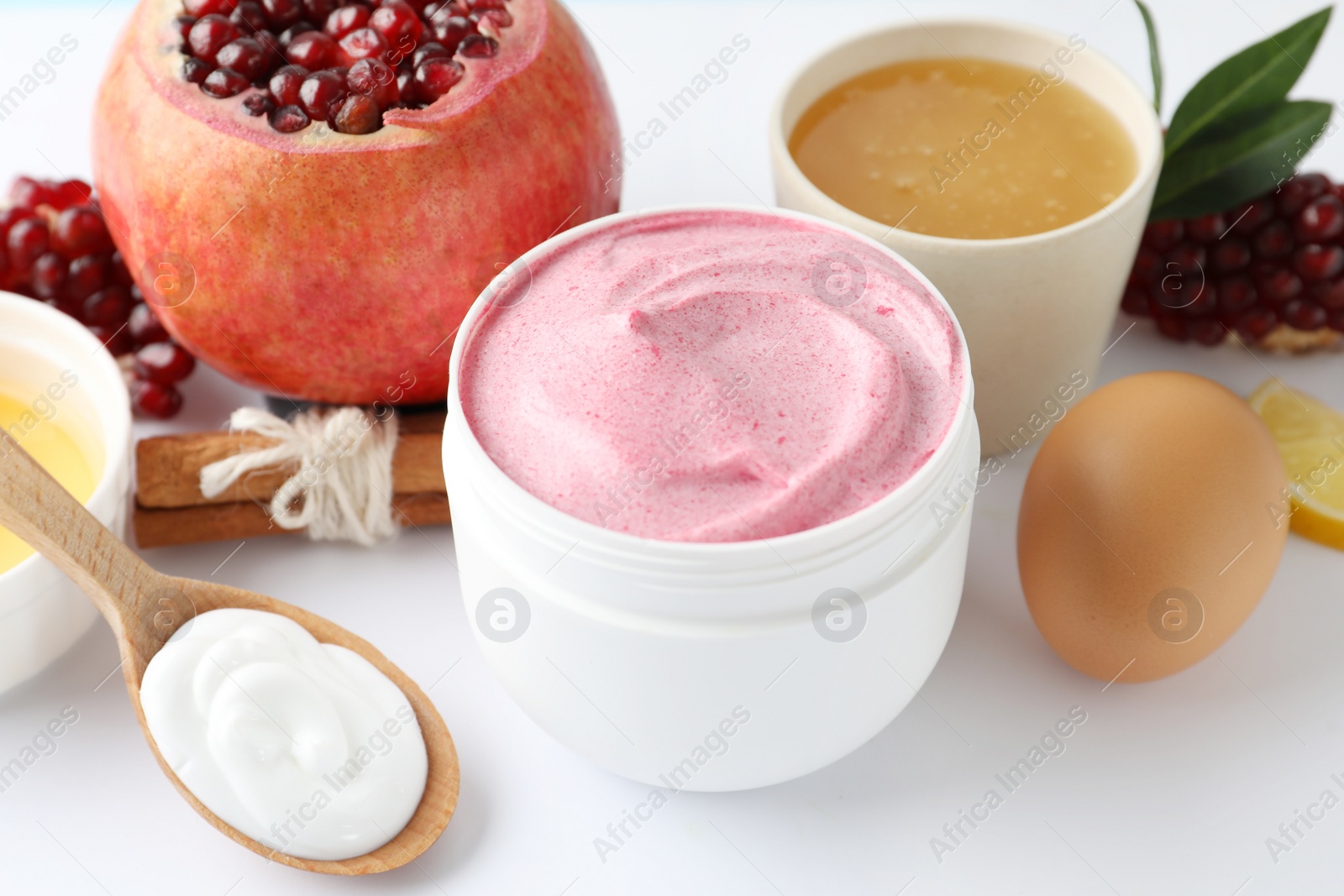 Photo of Jar of facial mask, pomegranate and fresh ingredients on white background. Natural organic cosmetics