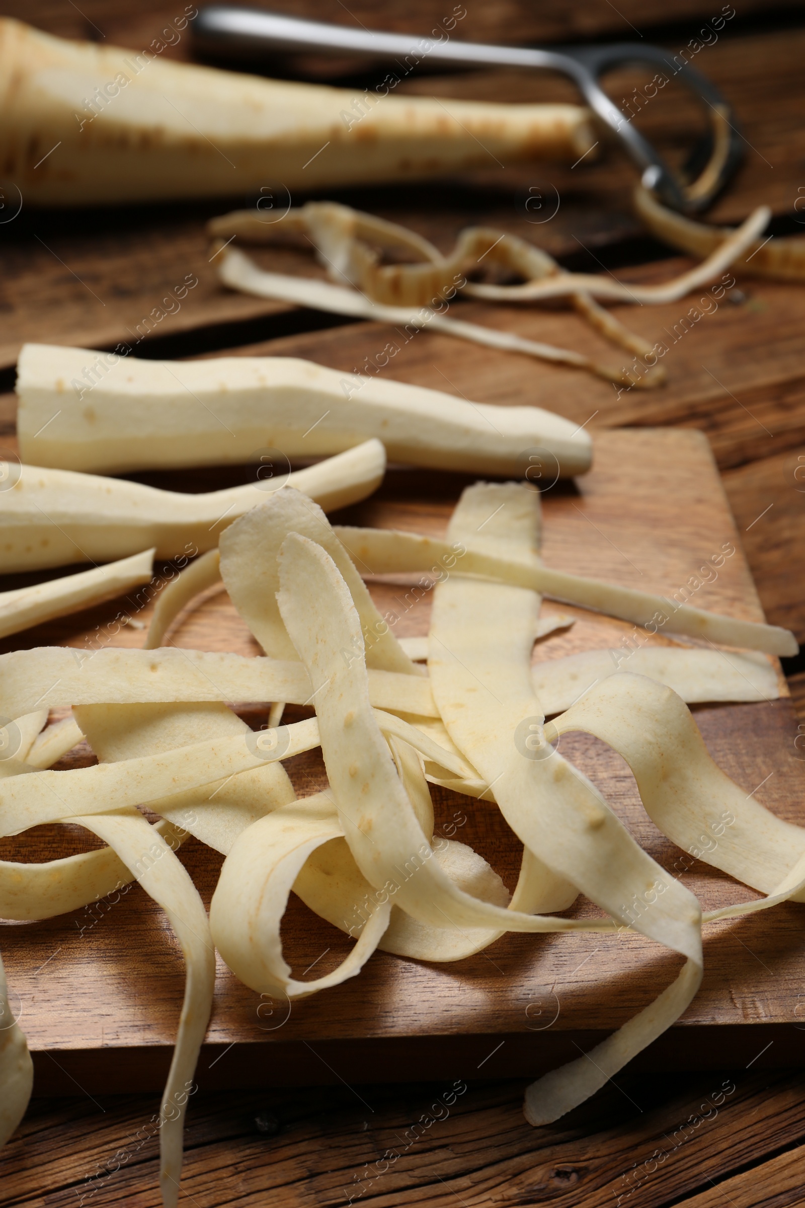 Photo of Peeled fresh parsnips and strips on wooden table
