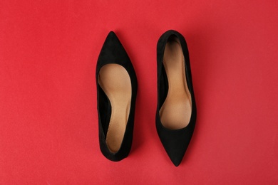 Pair of female shoes on color background, top view