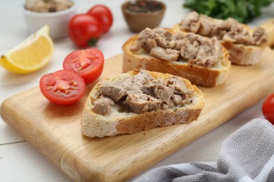 Photo of Tasty sandwiches with cod liver on white wooden table