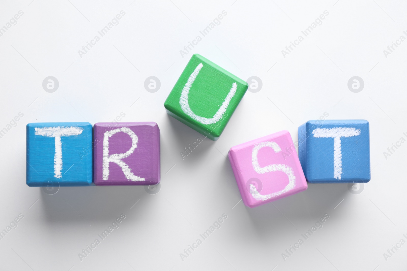 Photo of Cubes with word TRUST on white background, top view. Concept of jealousy