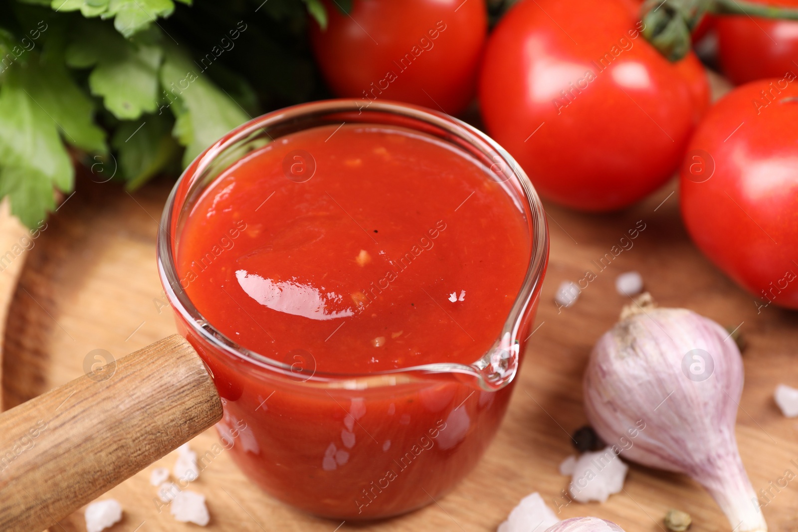 Photo of Delicious ketchup, salt and garlic on table, closeup. Tomato sauce