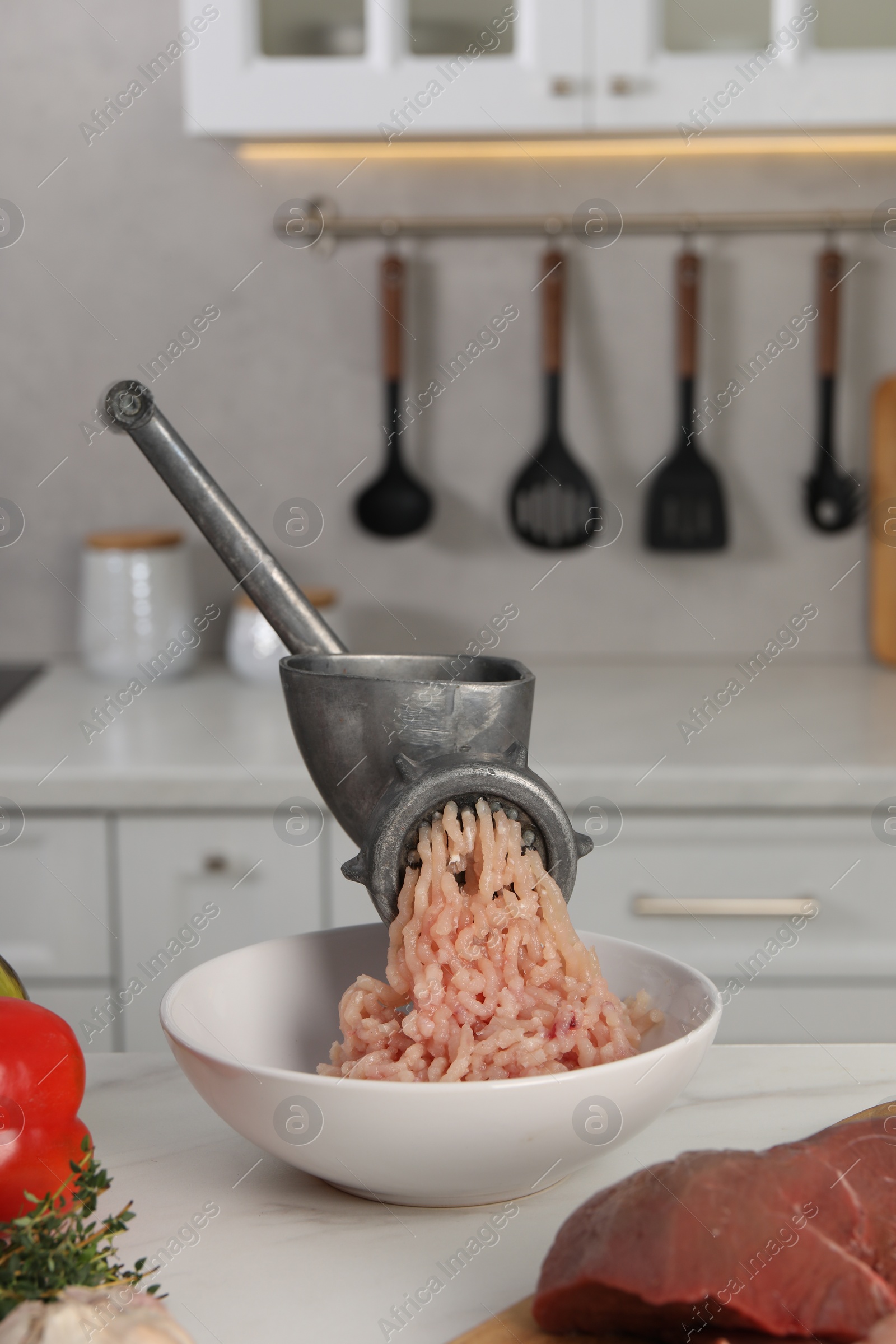 Photo of Metal meat grinder with chicken mince and products on white table in kitchen