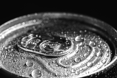 Aluminum can of beverage covered with water drops on black background, closeup