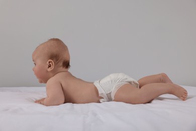 Cute little baby in diaper lying on bed
