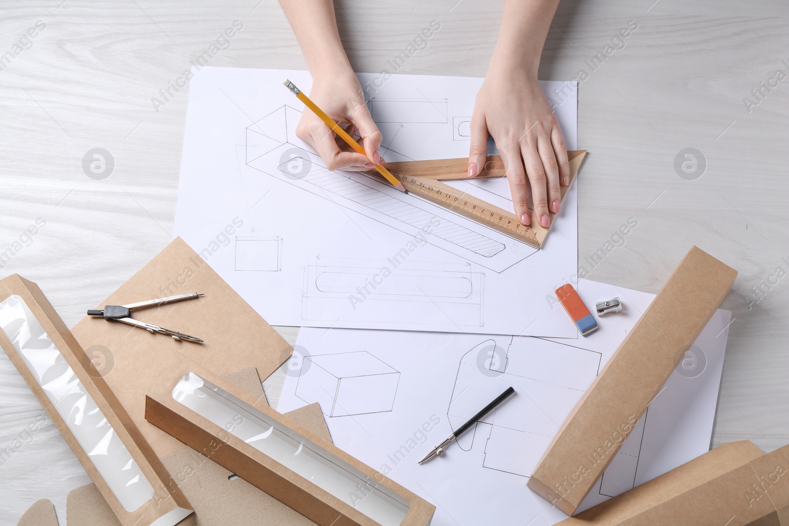 Photo of Woman creating packaging design at light wooden table, top view