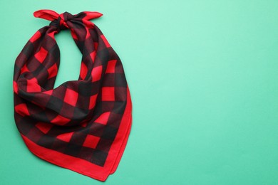 Photo of Tied red checkered bandana on turquoise background, top view. Space for text