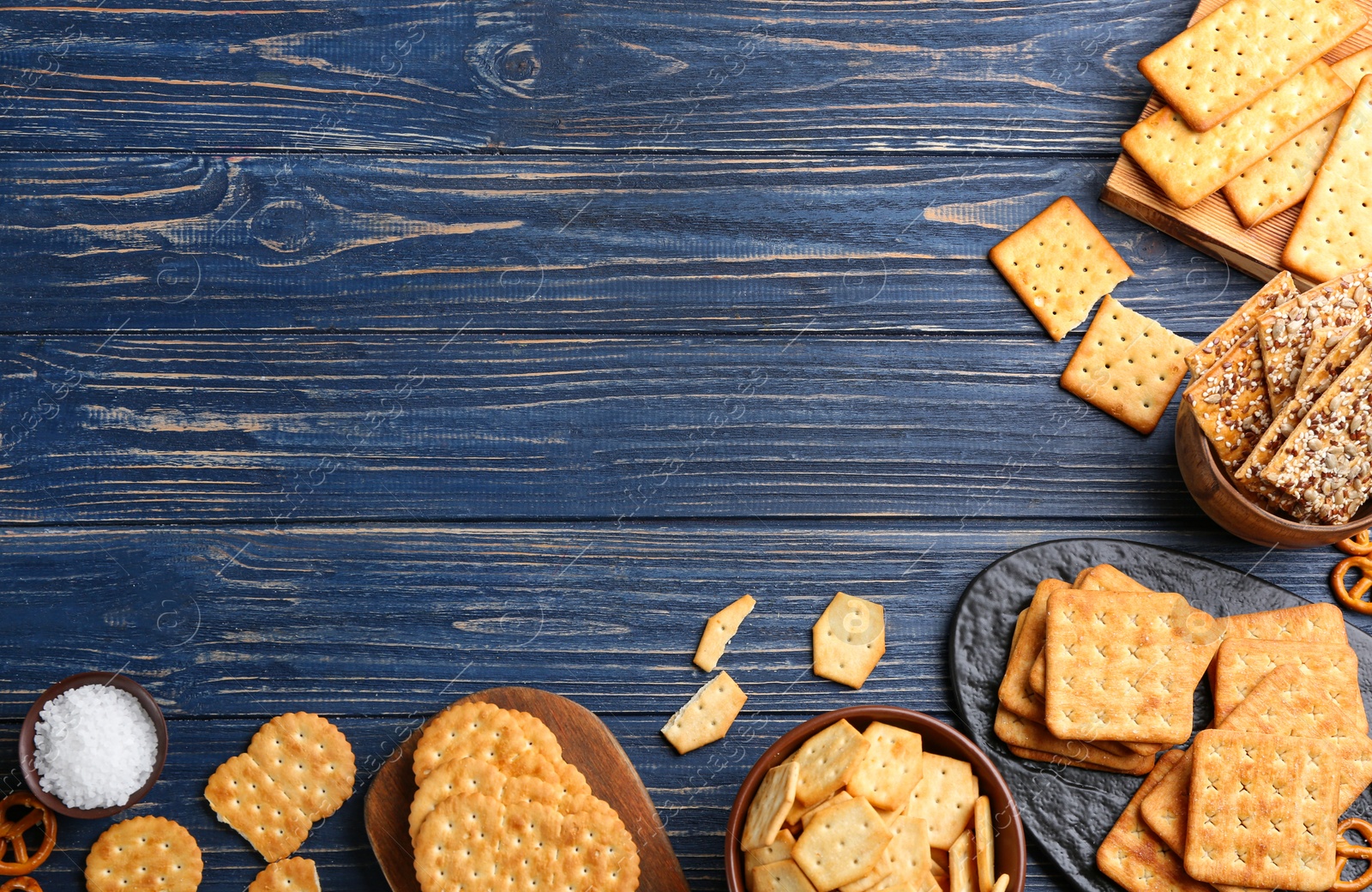 Photo of Many delicious crackers on blue wooden table, flat lay. Space for text