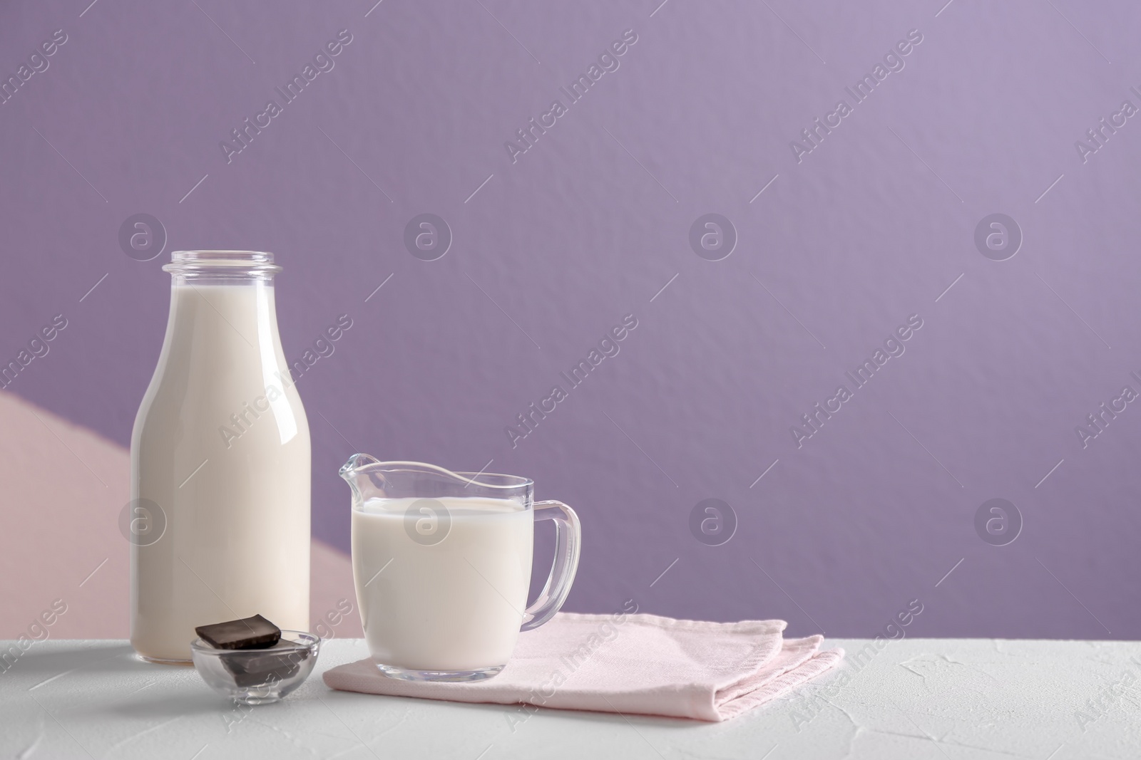 Photo of Composition with milk and chocolate on table against color background