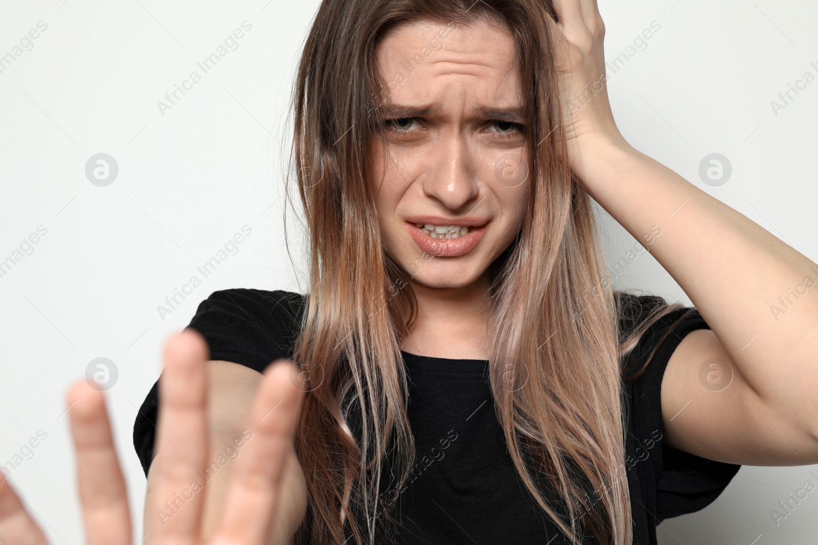 Photo of Desperate young woman on light background. Stop violence