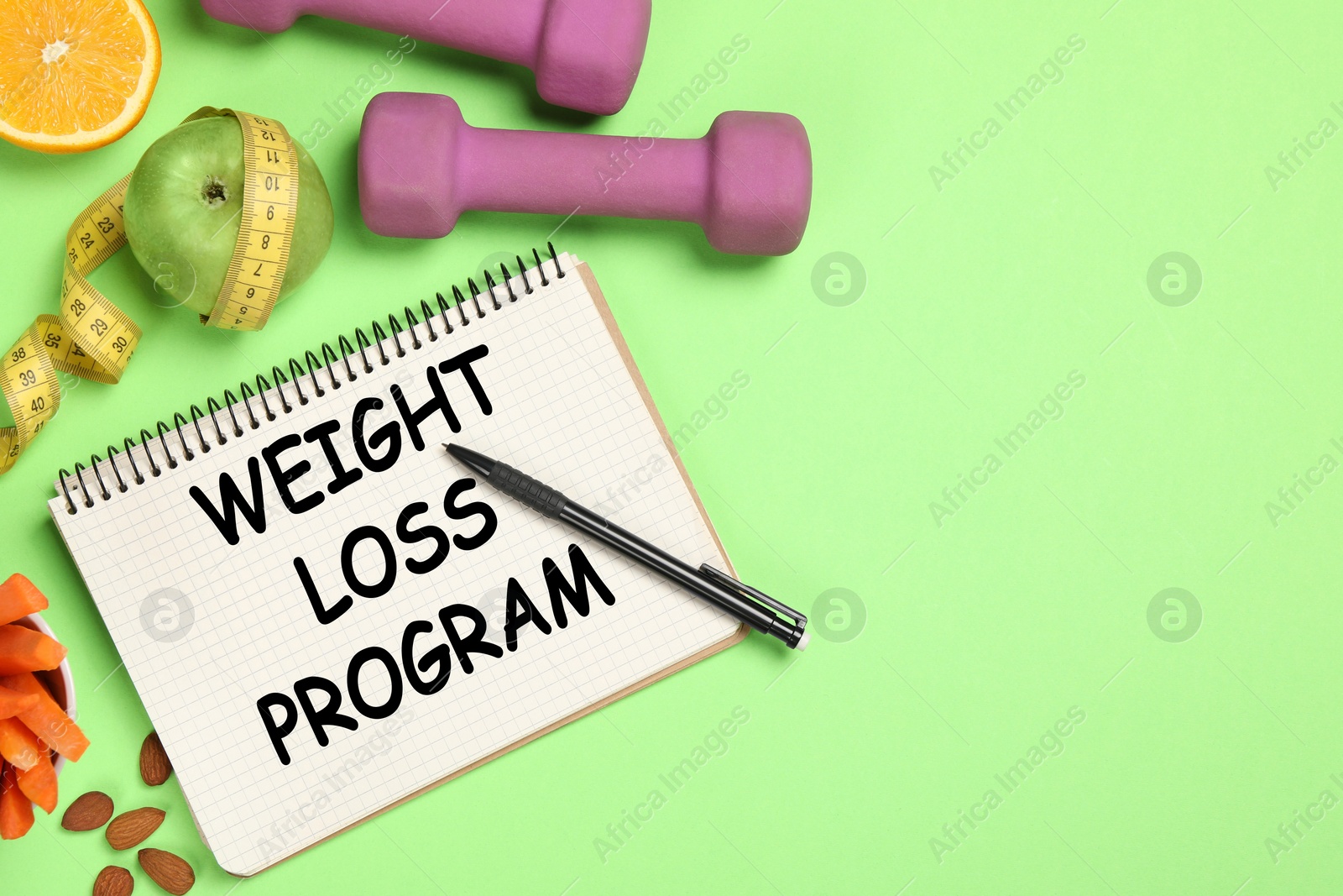 Photo of Weight loss concept. Flat lay composition with notebook, dumbbells and different products on green background, space for text