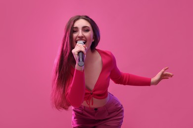 Photo of Emotional woman with microphone singing on pink background