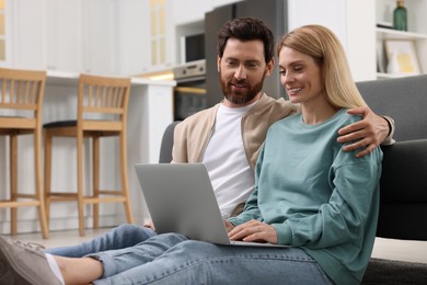 Photo of Happy couple spending time together and using laptop at home