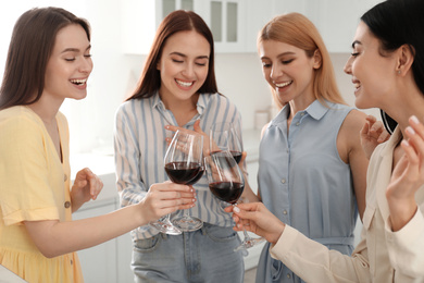 Photo of Beautiful young ladies clinking glasses of wine in kitchen. Women's Day