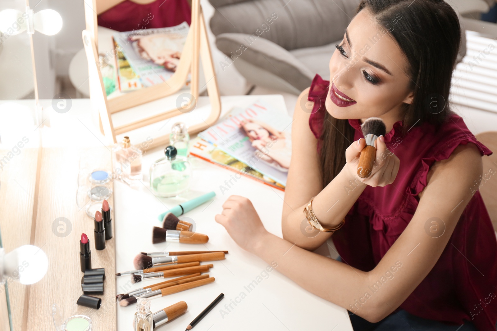 Photo of Portrait of beautiful woman applying makeup indoors