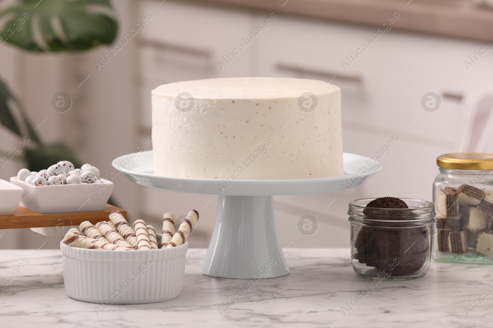 Photo of Delicious cake and sweets for decoration on white marble table in kitchen