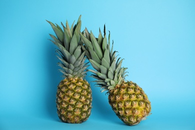 Photo of Ripe juicy pineapples on light blue background