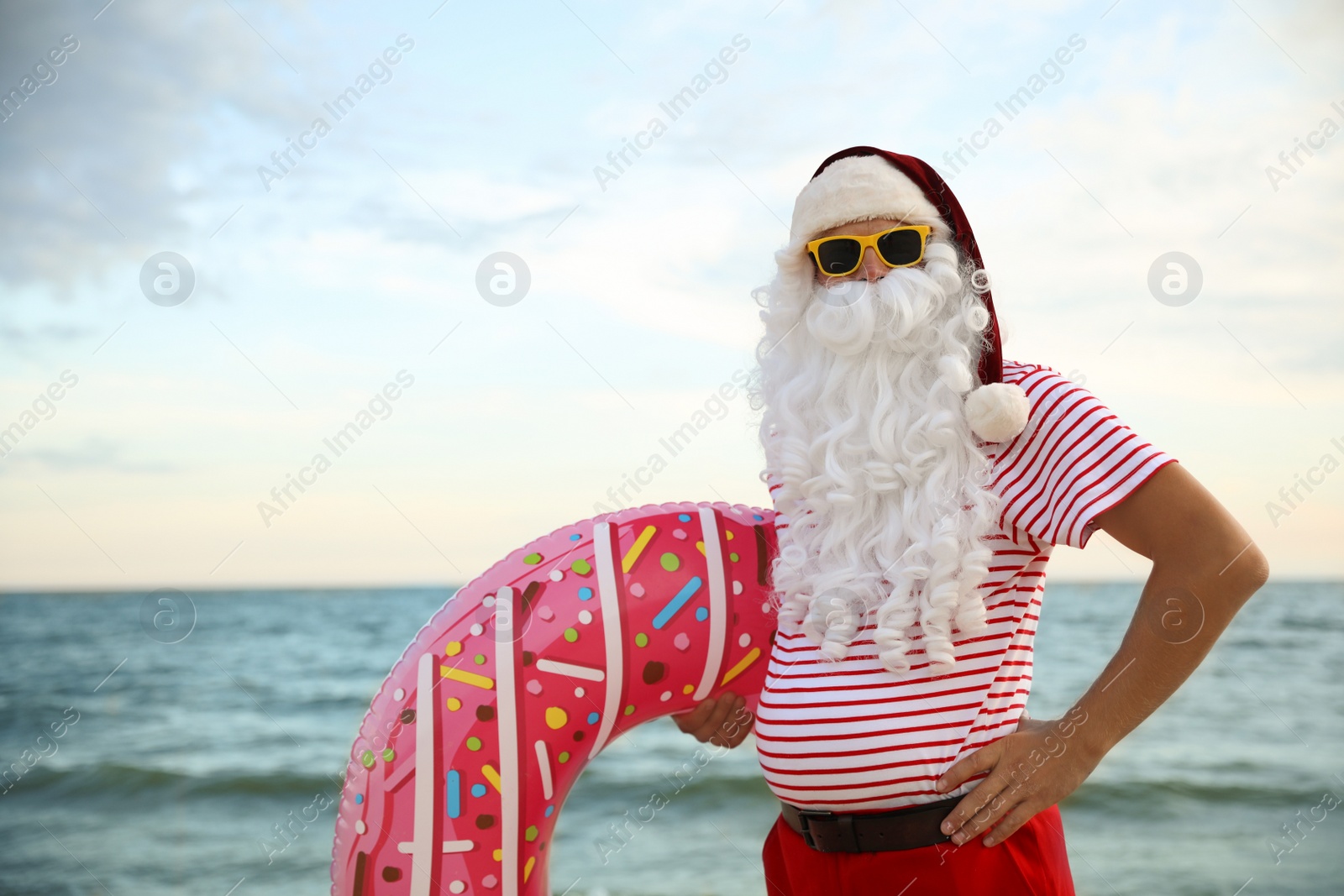 Photo of Santa Claus with inflatable ring on beach, space for text. Christmas vacation