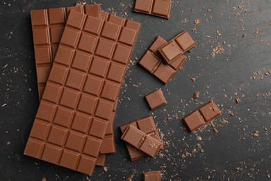 Pieces of tasty chocolate on grey table, flat lay