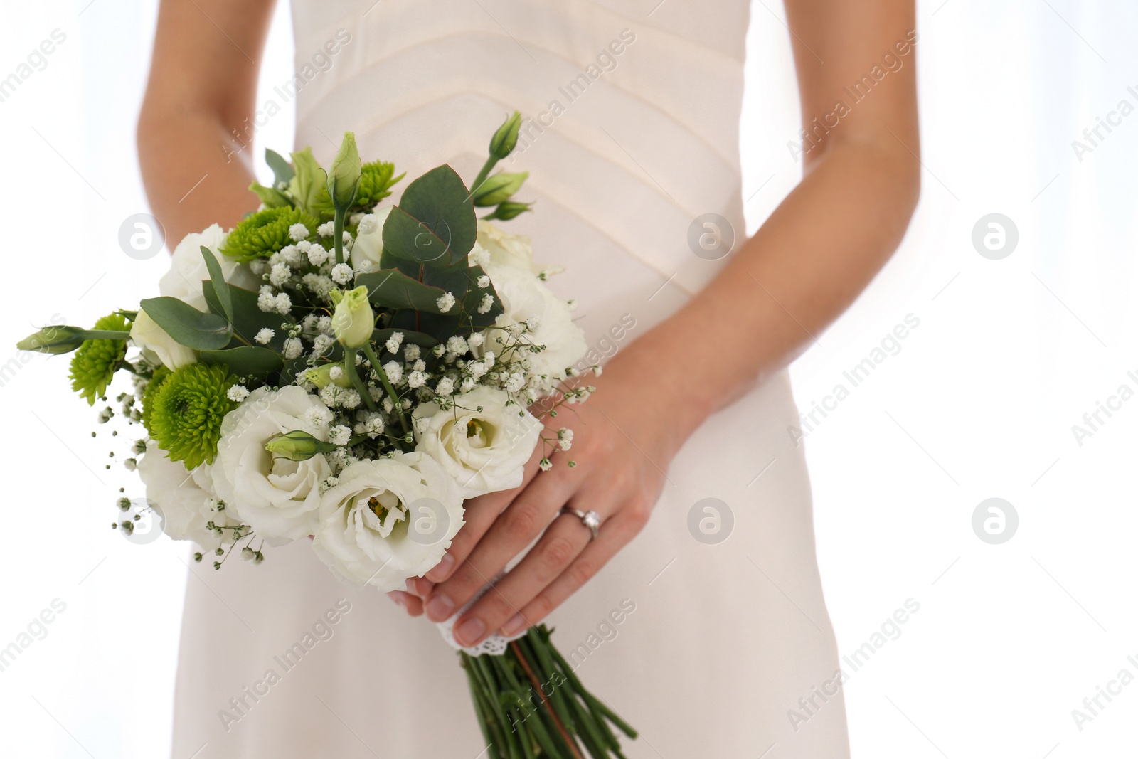 Photo of Bride holding beautiful bouquet with Eustoma flowers indoors, closeup