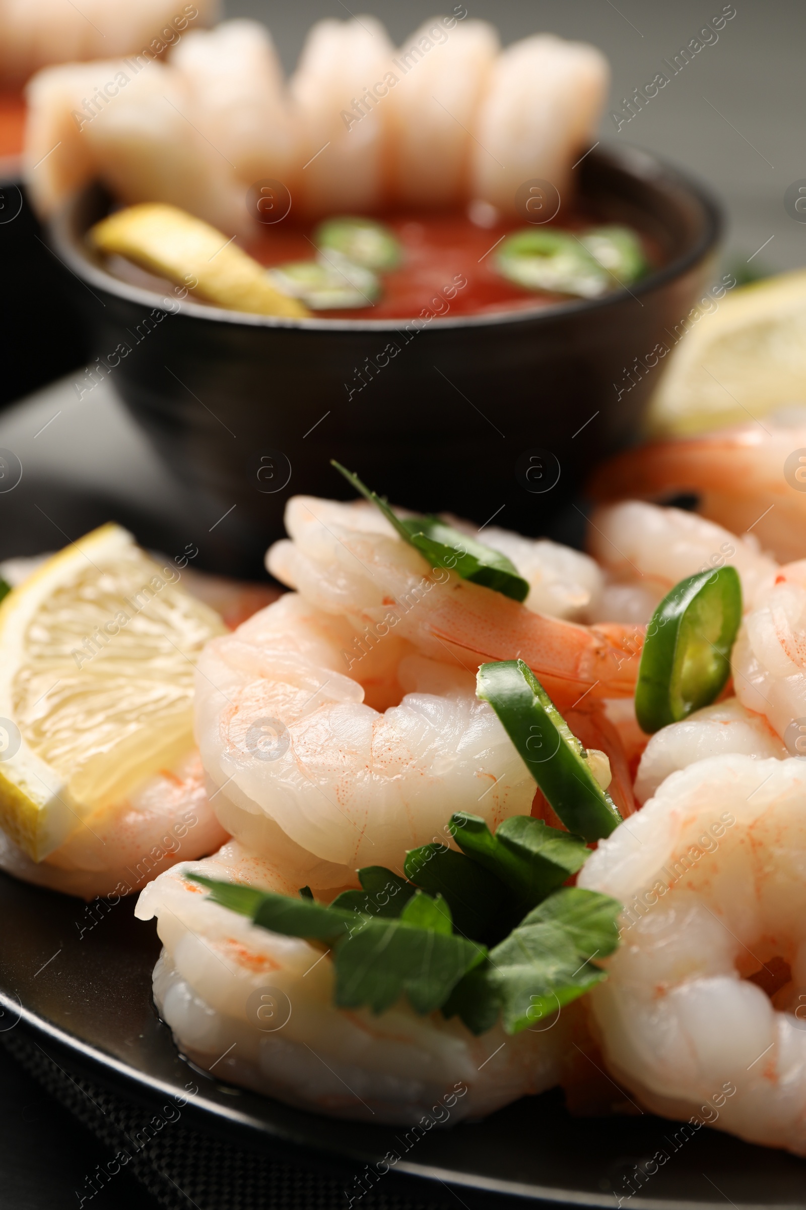 Photo of Tasty boiled shrimps with cocktail sauce, chili, parsley and lemon on table, closeup