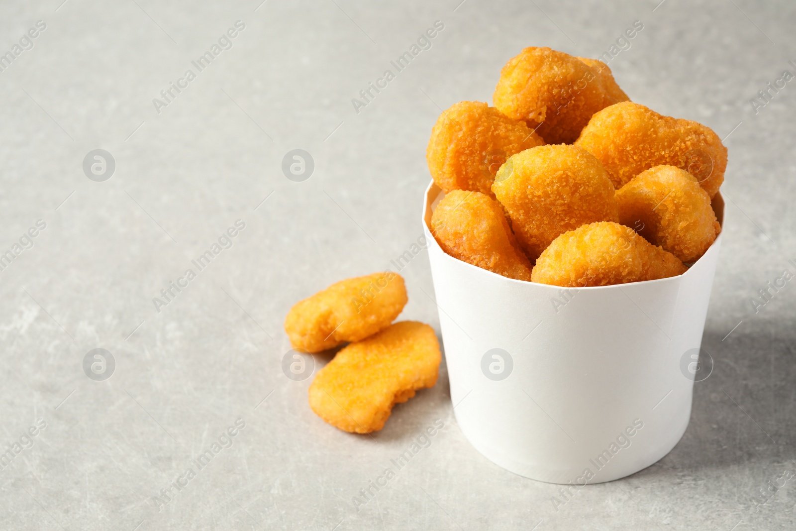 Photo of Delicious fried chicken nuggets on light grey table. Space for text