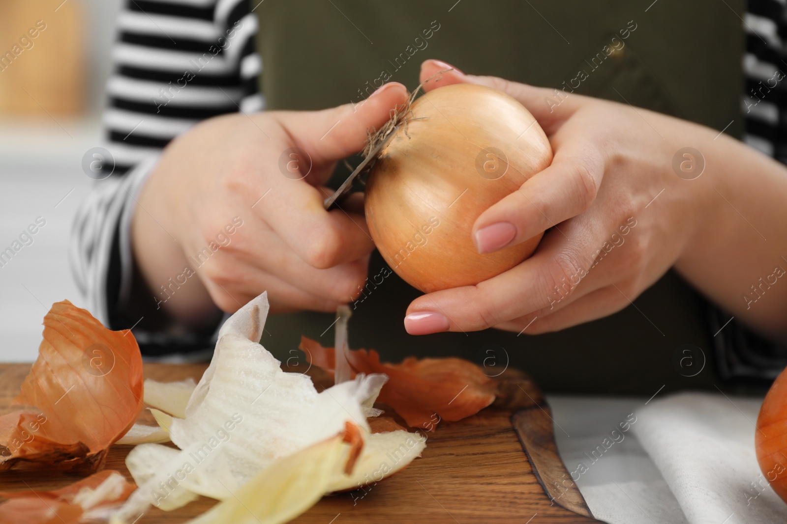 Photo of Woman peeling fresh onion with knife at white marble table, closeup