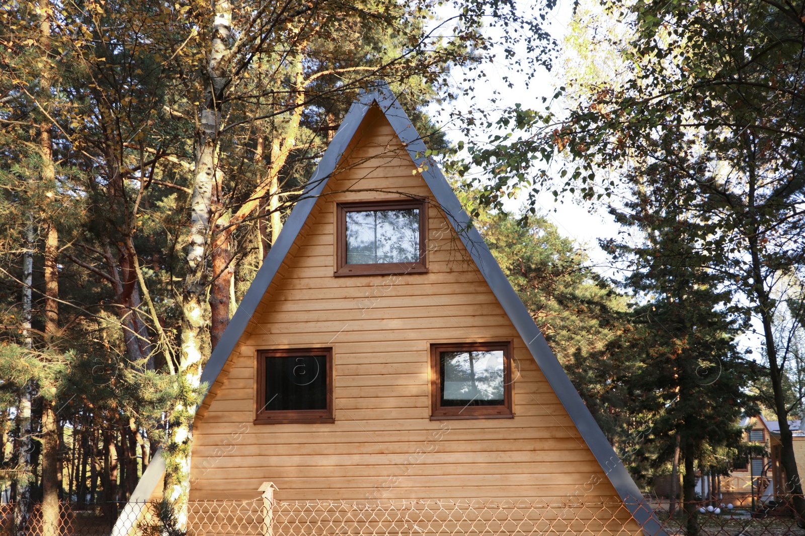 Photo of Picturesque view of modern wooden house near forest on sunny day