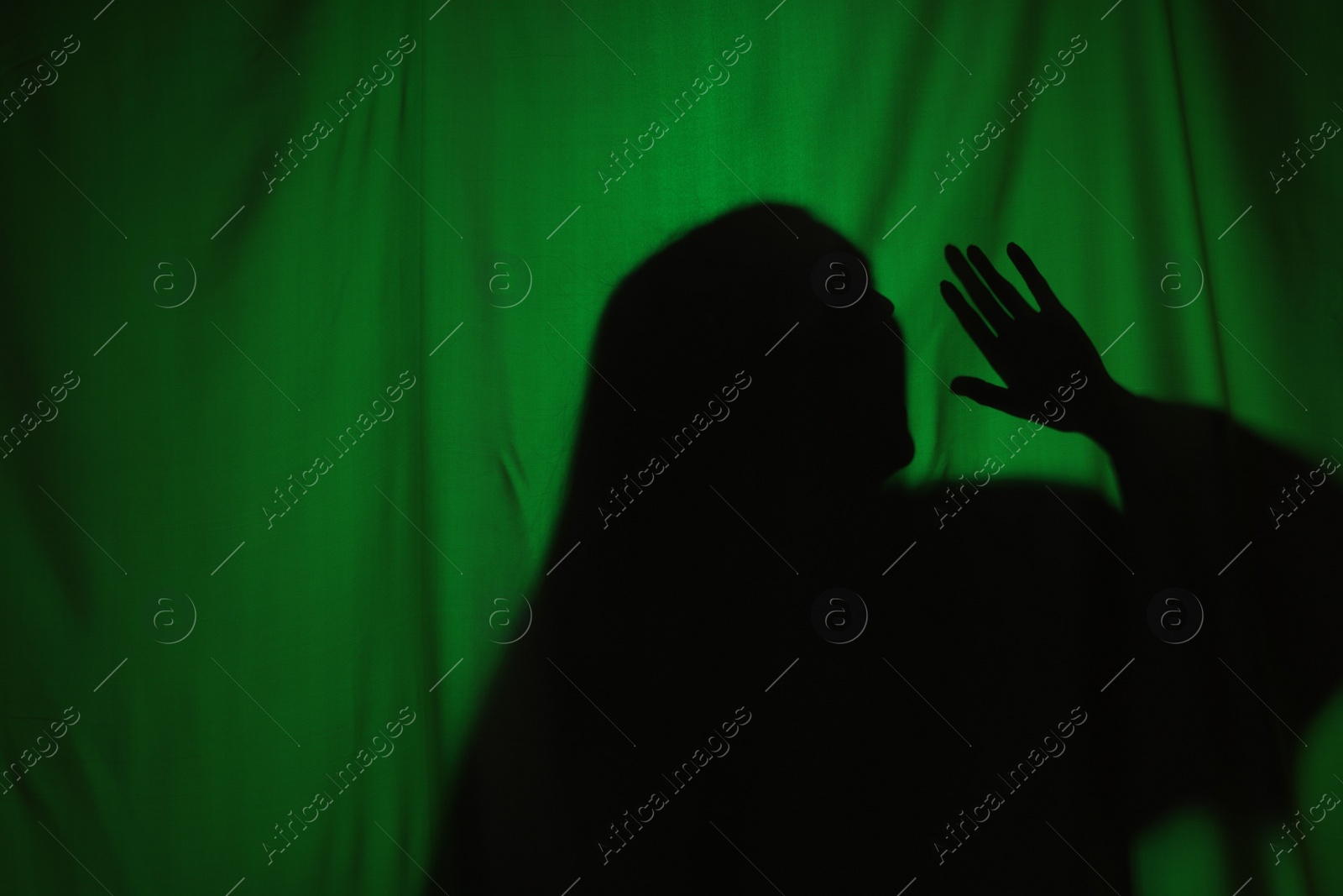 Photo of Silhouette of creepy ghost behind dark green cloth, space for text