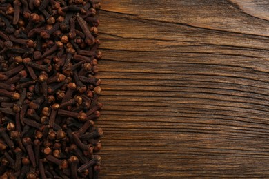Photo of Aromatic dry cloves on wooden table, flat lay. Space for text