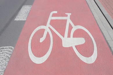 Red bike lane with painted white bicycle sign on sunny day