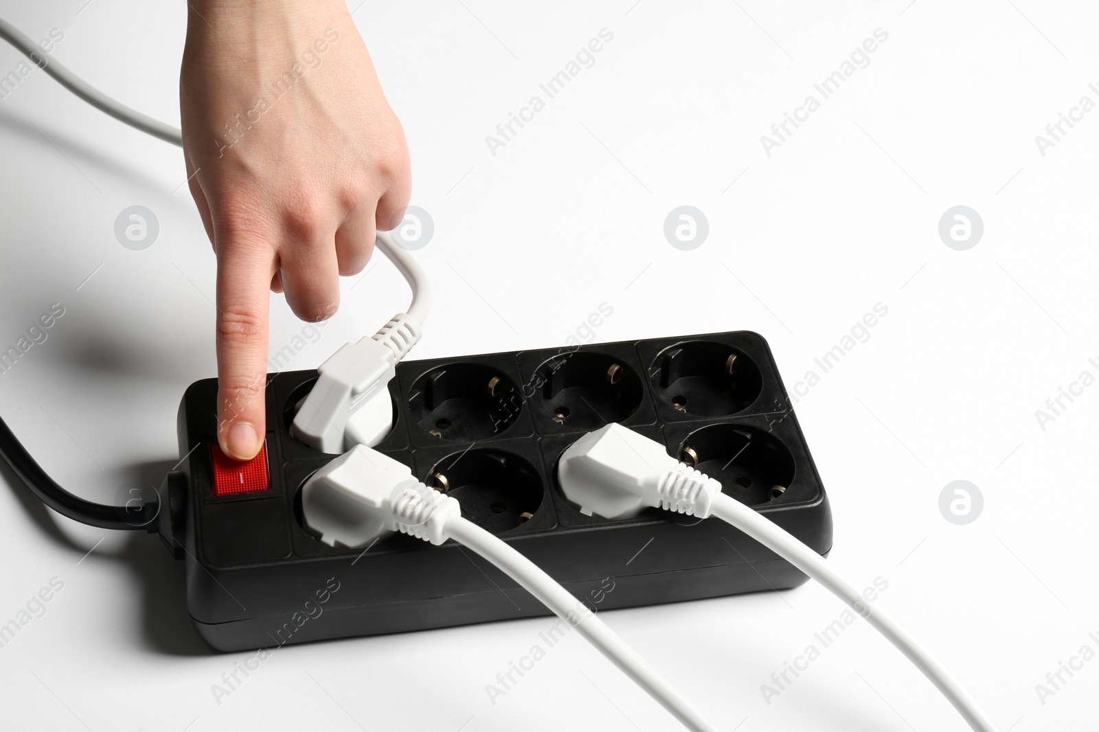 Photo of Woman pressing power button of extension cord on white background, closeup. Electrician's equipment