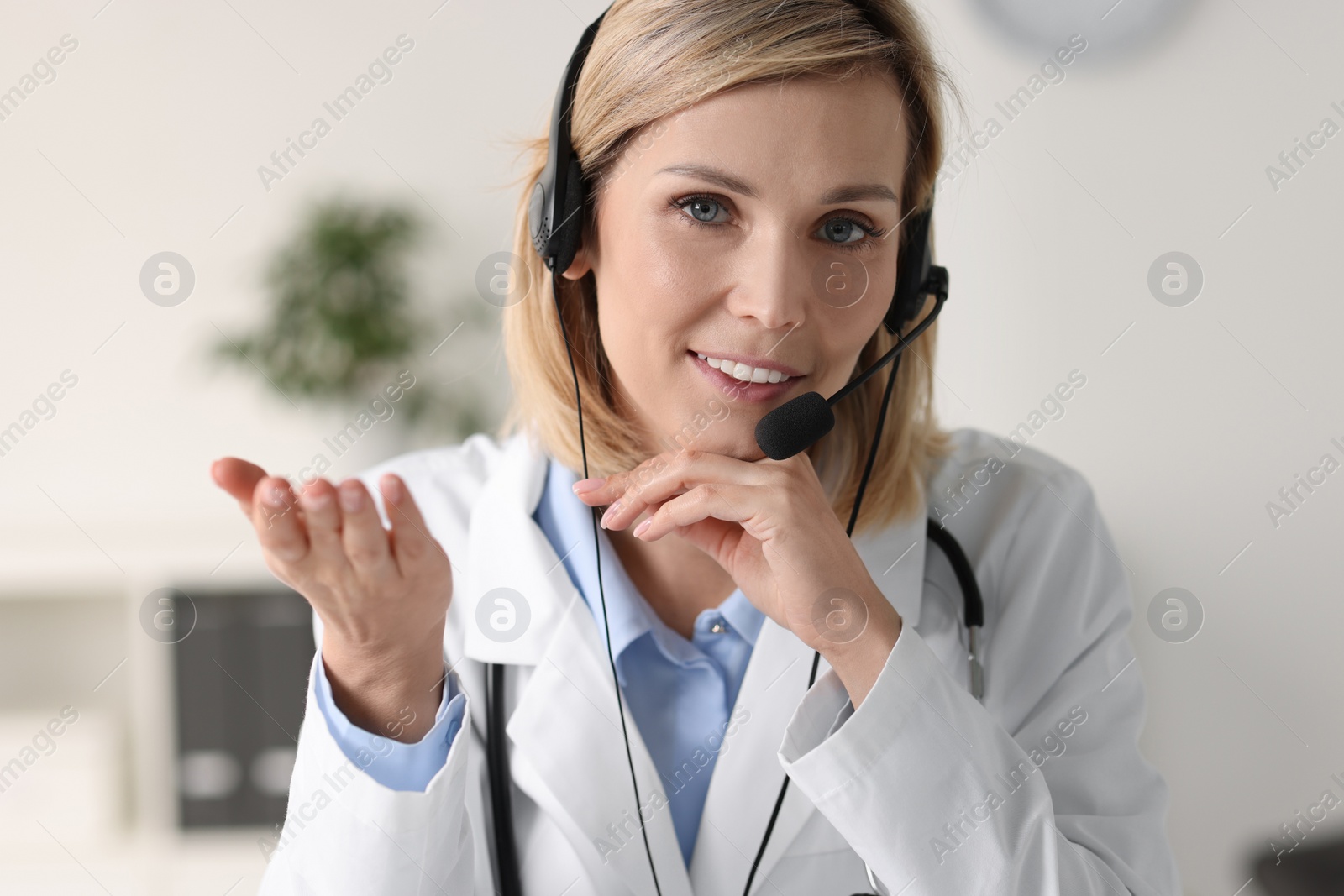 Photo of Smiling doctor wearing headphones having online in office