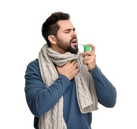 Young man with scarf using throat spray on white background