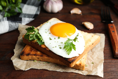 Photo of Tasty fried egg with toasts and parsley on wooden table, closeup