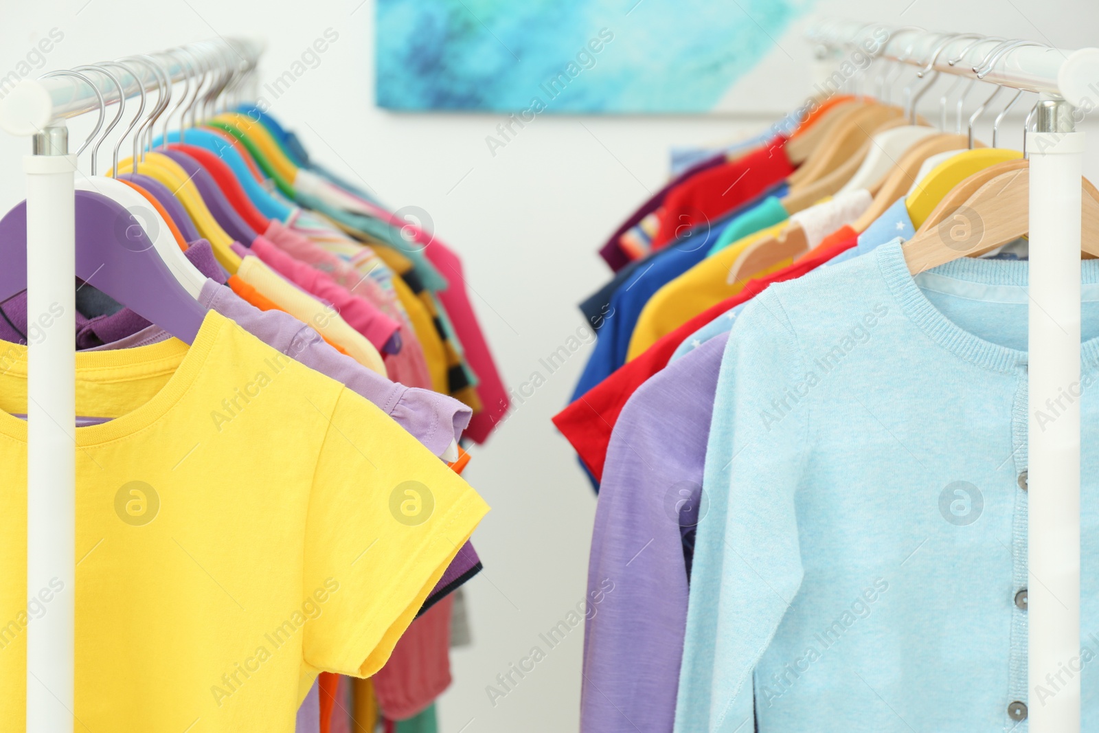 Photo of Different child's clothes hanging on racks indoors, closeup