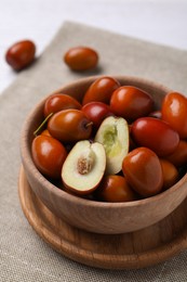Photo of Fresh Ziziphus jujuba fruits in wooden bowl on table, closeup