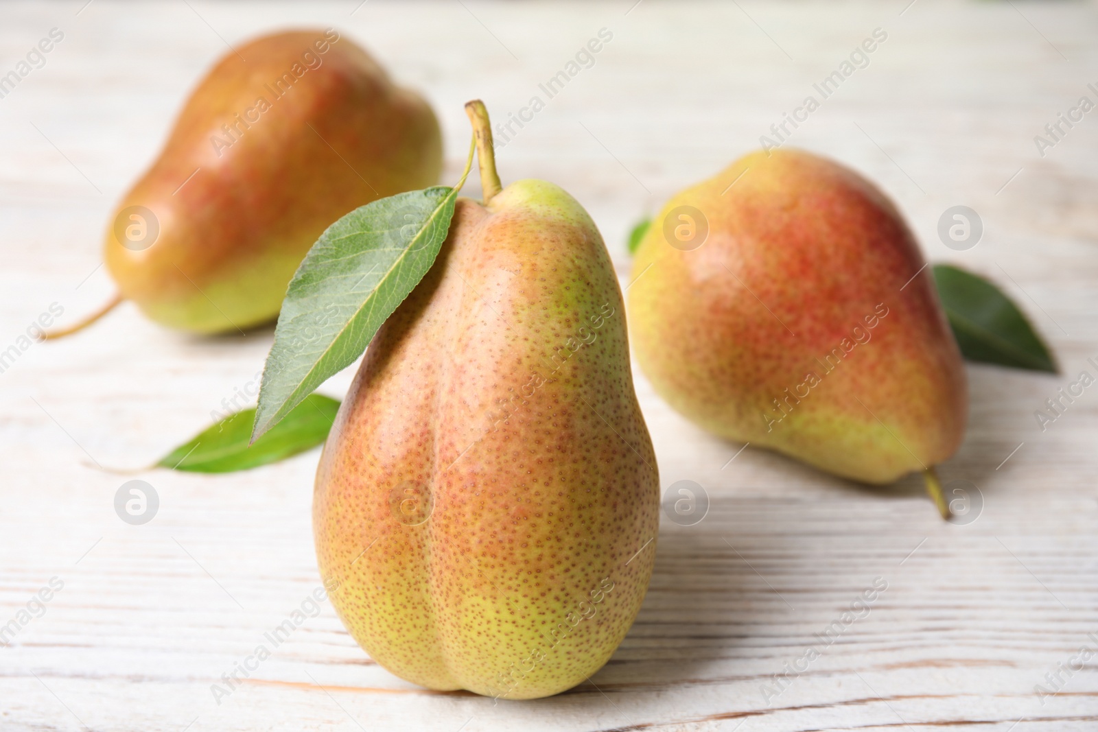 Photo of Ripe juicy pears on white wooden table