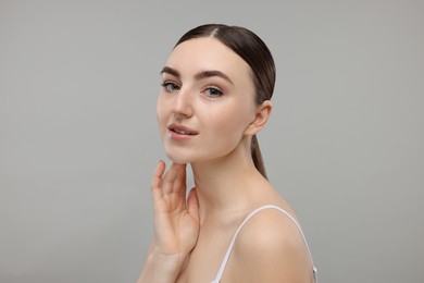 Photo of Beautiful woman touching her neck on grey background