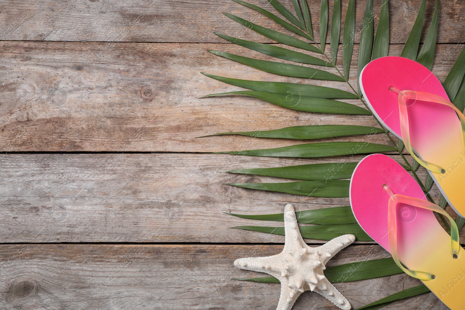 Photo of Flat lay composition with flip flops and starfish on wooden background. Beach objects