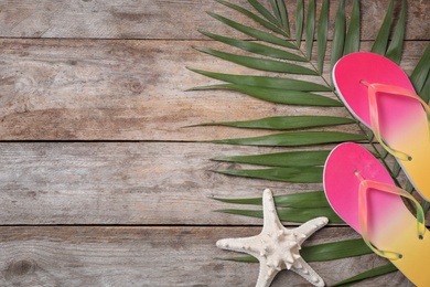 Photo of Flat lay composition with flip flops and starfish on wooden background. Beach objects