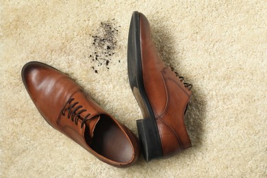 Photo of Brown shoes and mud on beige carpet, top view